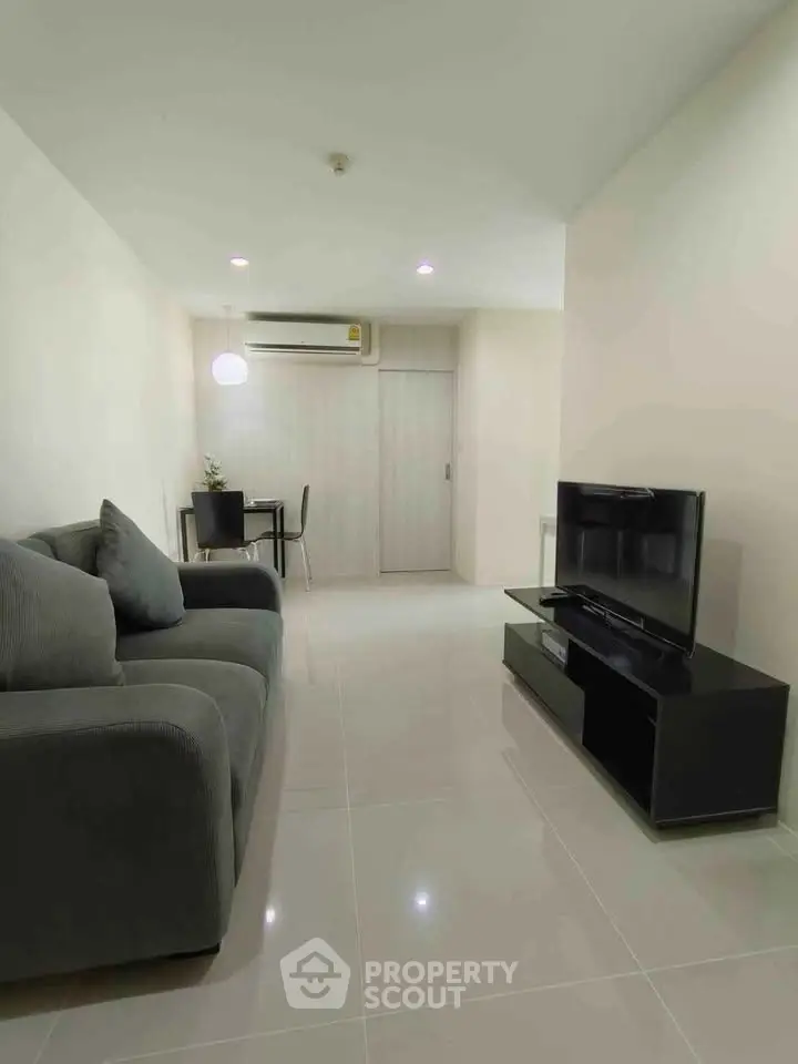 Modern living room with sleek furniture and minimalist design, featuring a cozy sofa and flat-screen TV.
