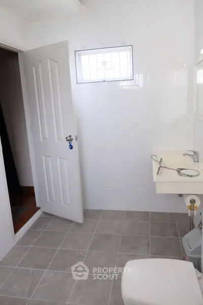 Spacious bathroom with modern fixtures and tiled flooring in a bright home.