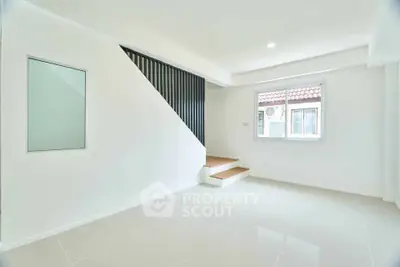 Bright minimalist living room with modern staircase and large window