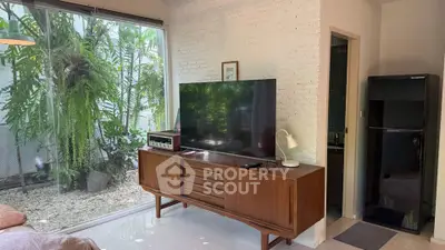 Stylish living room with large TV, vintage furniture, and garden view.