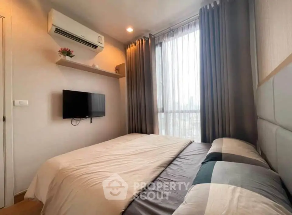 Cozy bedroom with modern decor, featuring a wall-mounted TV and air conditioning, perfect for relaxation.