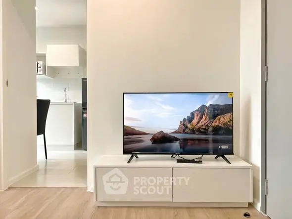 Modern living room with sleek TV setup and glimpse of contemporary kitchen.