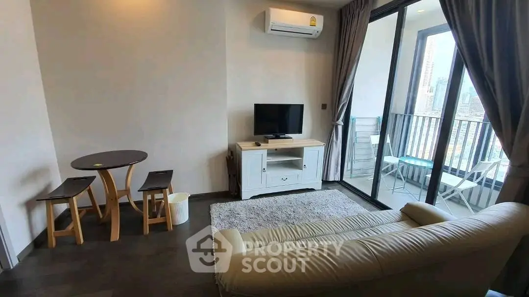 Modern living room with balcony view, cozy seating, and stylish decor in urban apartment.