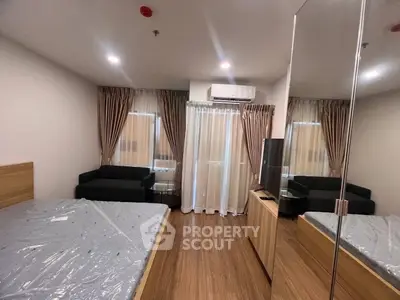 Modern bedroom with wooden flooring, cozy bed, and stylish curtains in a well-lit apartment.