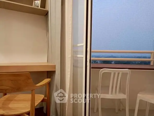 Cozy study area with balcony view, featuring wooden desk and chair, perfect for work-from-home setup.