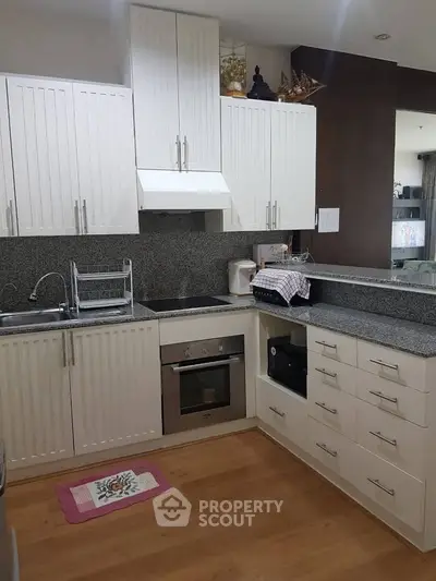 Modern kitchen with white cabinets and granite countertops in a cozy apartment.