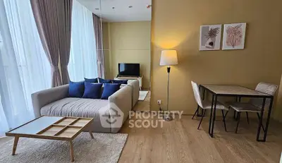 Modern living room with stylish decor, cozy sofa, and natural light from large windows.