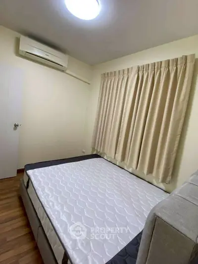 Cozy bedroom with air conditioning and natural light, featuring a comfortable bed and elegant curtains.