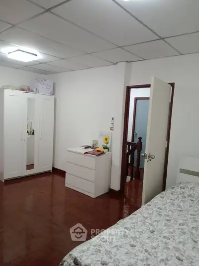 Cozy bedroom with white furniture and floral bedding, perfect for a peaceful retreat.