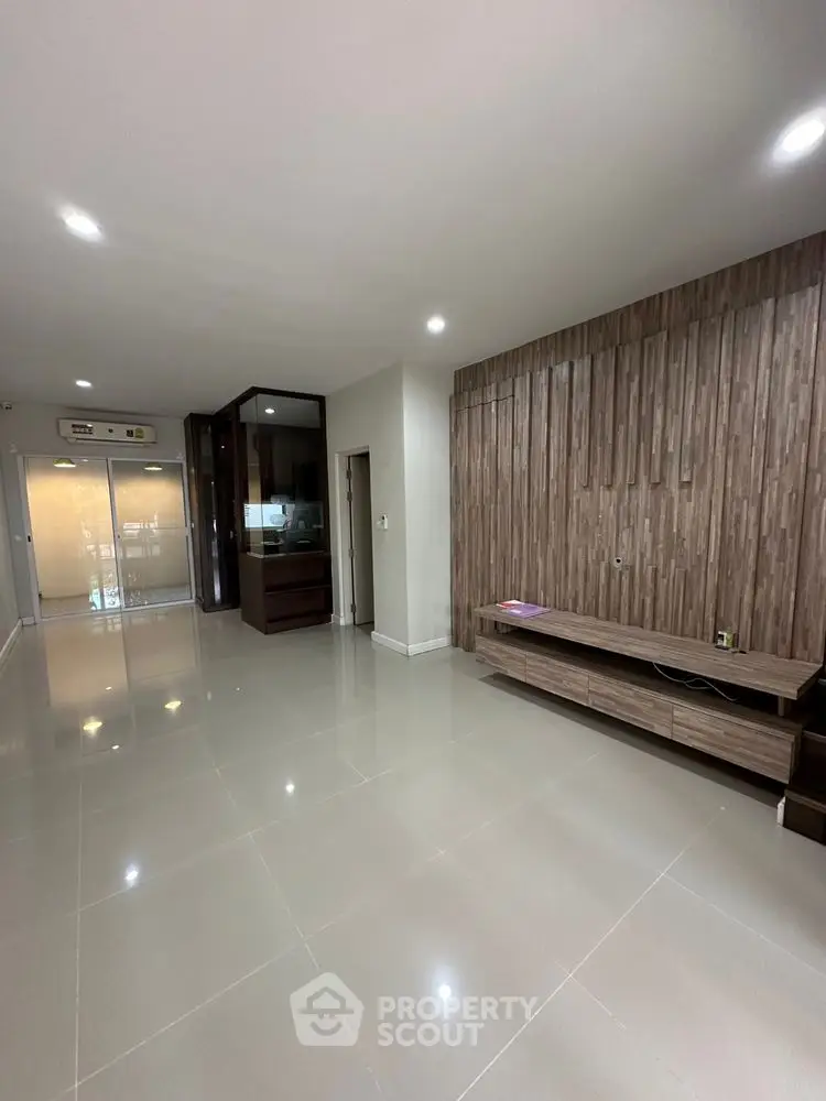 Spacious modern living room with sleek wooden accents and glossy tile flooring.