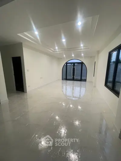 Spacious modern living room with elegant ceiling design and large windows for natural light.