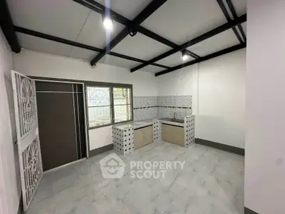 Spacious kitchen with modern tile flooring and open layout, featuring ample natural light and sleek cabinetry.