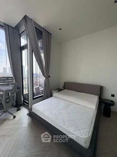 Modern bedroom with city view, featuring a sleek bed and stylish workspace in a high-rise apartment.