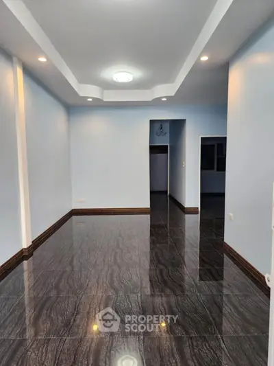 Spacious empty room with glossy flooring and recessed lighting, perfect for customization.