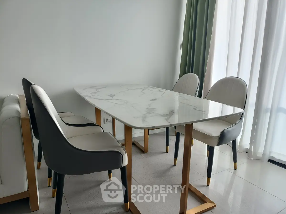 Elegant dining area with marble table and stylish chairs in modern apartment.