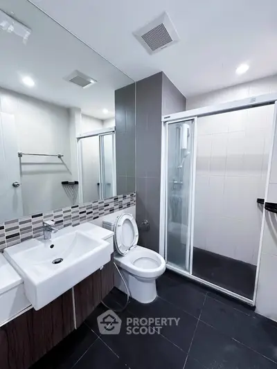 Modern bathroom with sleek design, featuring a glass shower enclosure and stylish sink.
