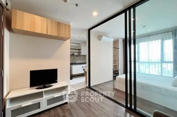 Modern apartment interior with open layout and glass partition, featuring cozy living area and bedroom.