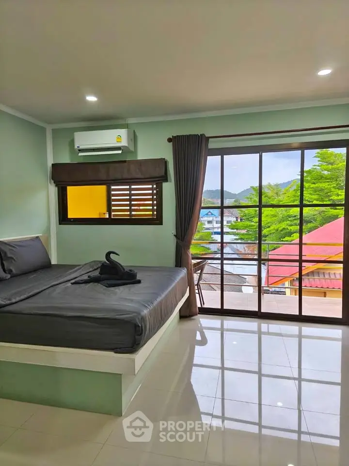 Spacious bedroom with large windows offering a scenic view and modern furnishings.