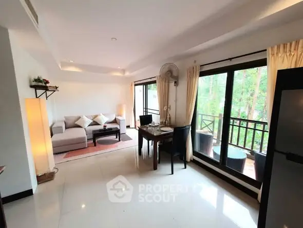 Spacious living room with large windows and balcony access, offering a serene view of greenery.