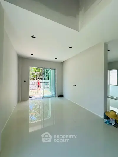 Spacious modern living room with glossy floors and large windows offering natural light.