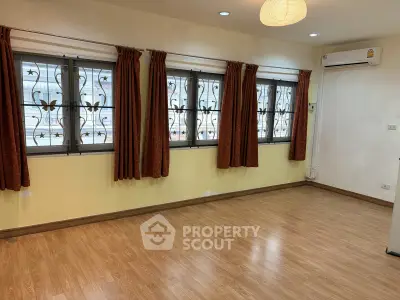 Spacious empty room with hardwood floors and large windows, perfect for customization.