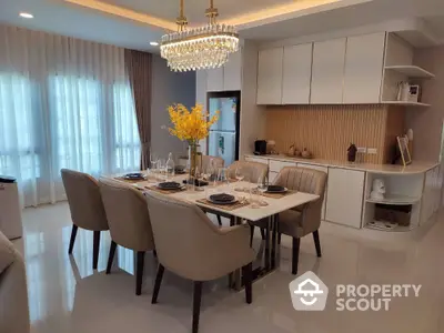 Elegant dining area with chandelier and modern kitchen in luxury apartment