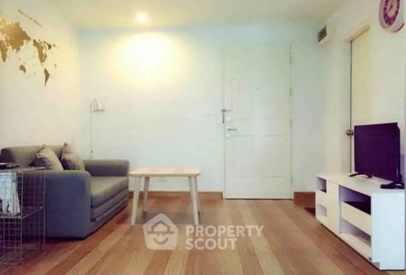 Cozy living room with modern decor and wooden flooring, featuring a comfortable sofa and TV unit.