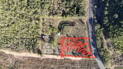 Aerial view of a large plot of land with road access and natural surroundings.