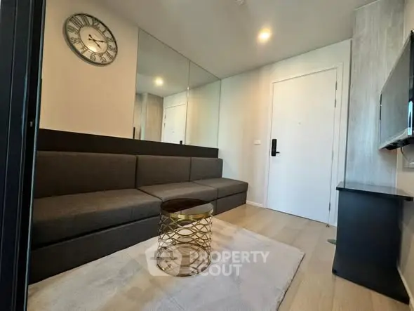 Modern living room with stylish sofa, wall clock, and elegant decor in a contemporary apartment.