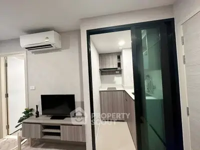 Modern compact living room with sleek kitchen and air conditioning unit, perfect for urban living.