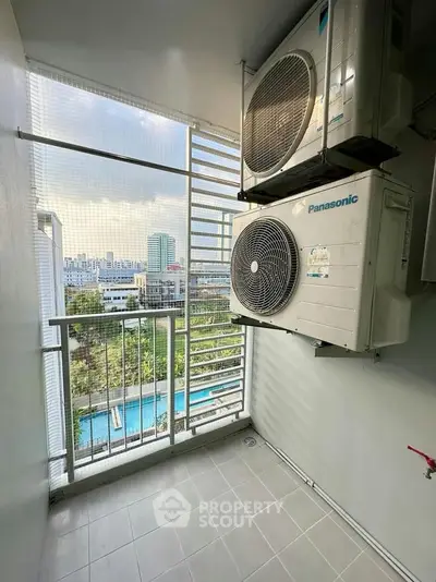 Modern balcony with air conditioning units and city view, overlooking a pool area.