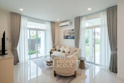 Spacious modern living room with elegant decor and large windows offering garden views.