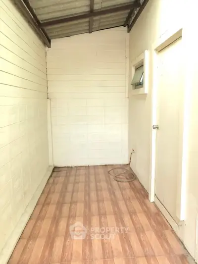 Compact storage room with wooden flooring and white walls, ideal for organizing household items.