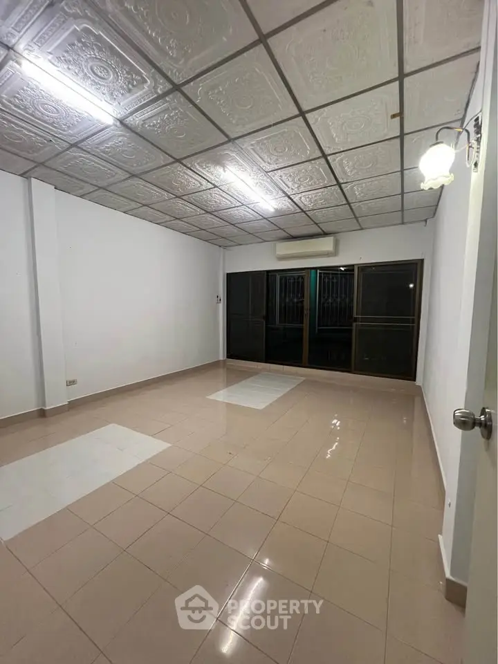 Spacious empty room with tiled flooring and decorative ceiling, ideal for customization.