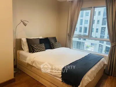 Cozy bedroom with modern decor and large window offering city view.