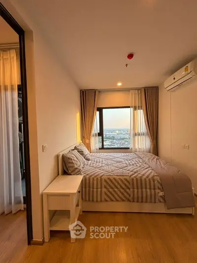 Cozy bedroom with city view and modern decor in high-rise apartment.