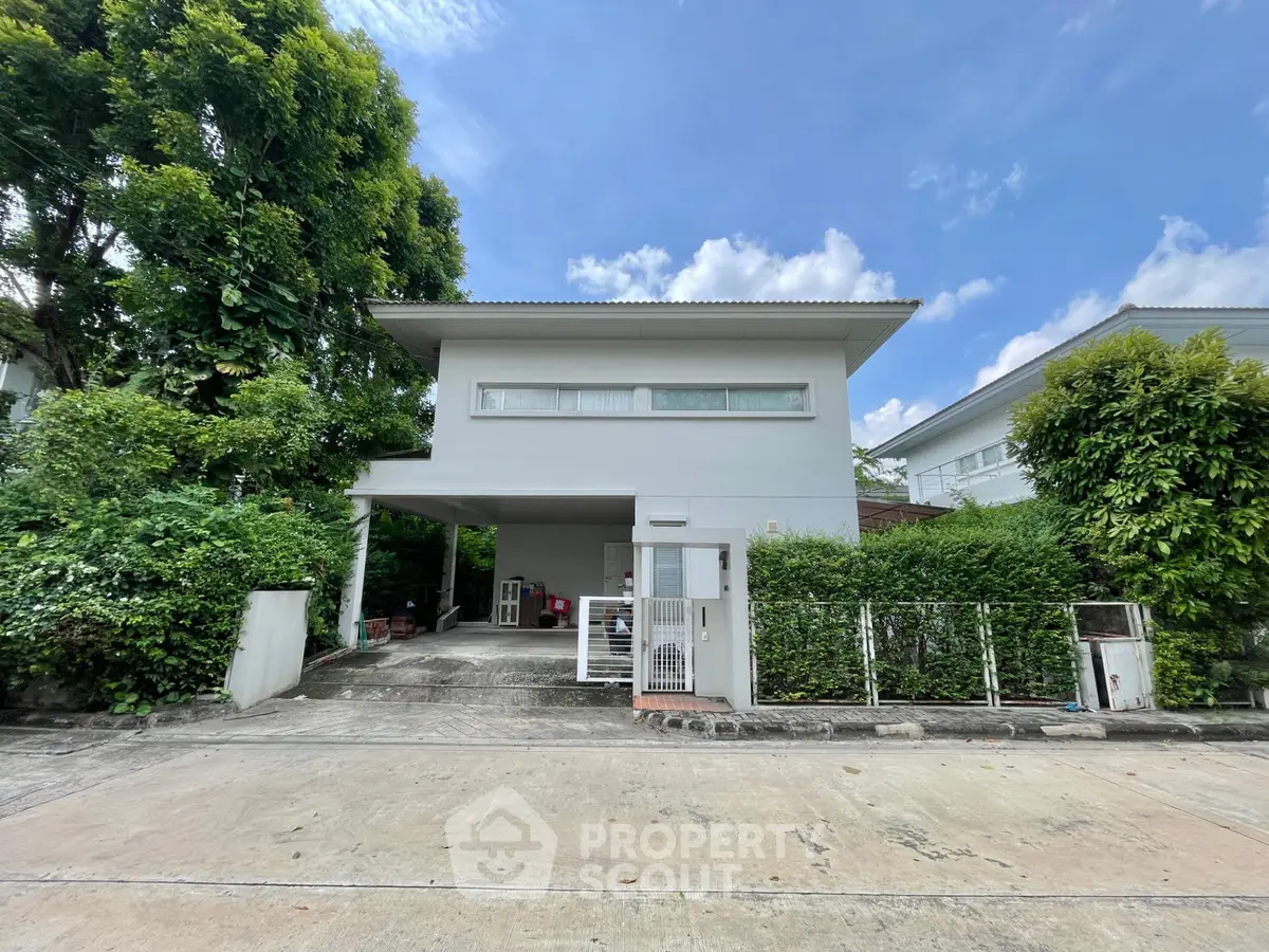 Modern two-story house with lush greenery and spacious driveway in a serene neighborhood.