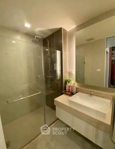 Modern bathroom with glass shower and sleek vanity in contemporary apartment.