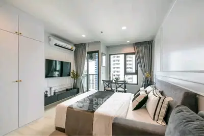 Luxurious modern bedroom with elegant decor and city view, featuring a sleek TV setup and stylish furnishings.