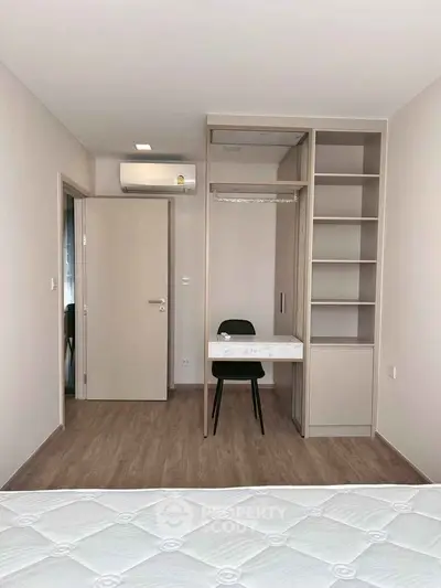 Modern bedroom with built-in wardrobe and desk, featuring minimalist design and wood flooring.