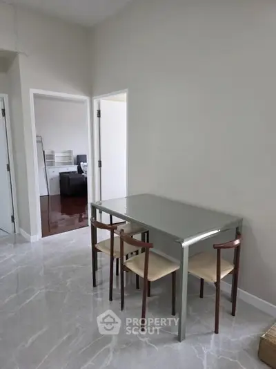Modern dining area with sleek table and chairs in a bright, minimalist apartment interior.