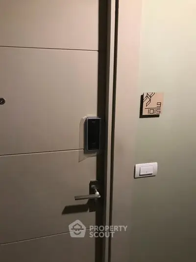 Modern apartment entrance with electronic lock and stylish room number plaque.