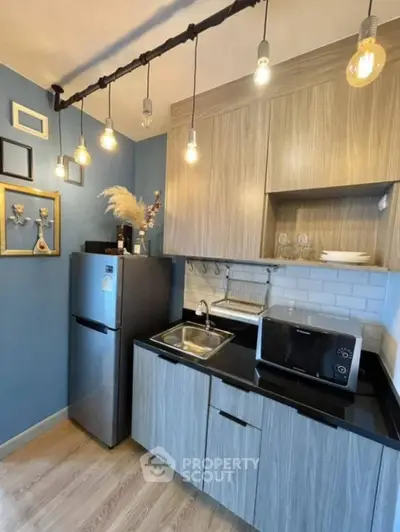 Modern kitchen with stylish lighting and sleek appliances in compact space