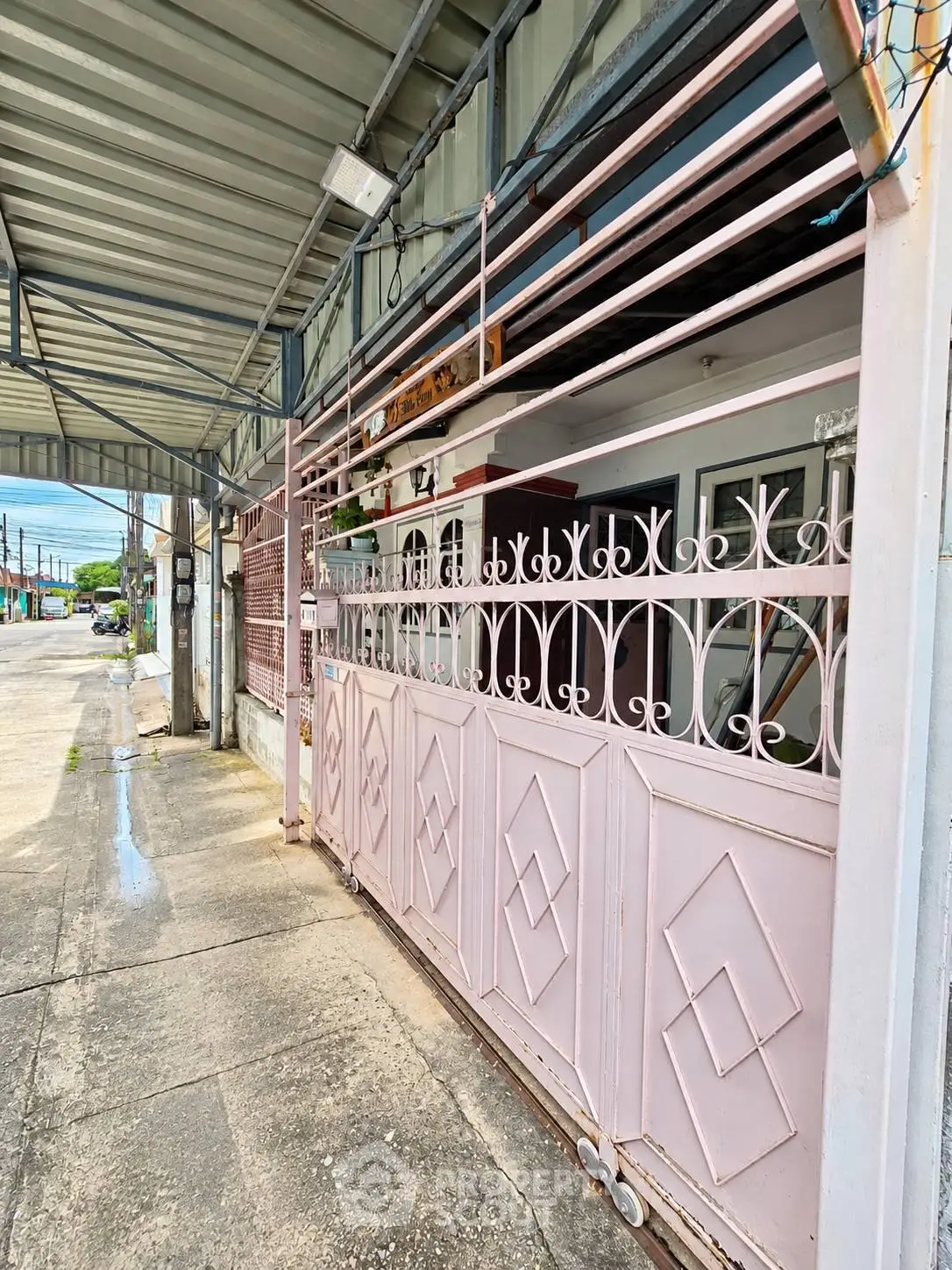 Charming residential entrance with decorative metal gate and covered walkway in urban setting.