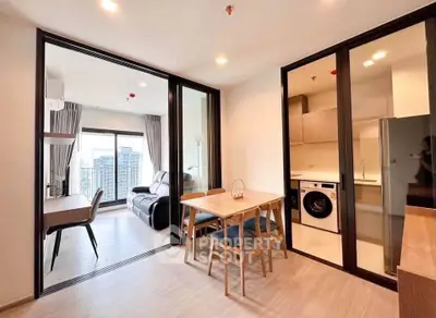 Modern apartment interior with open living and dining area, featuring a washing machine and city view.