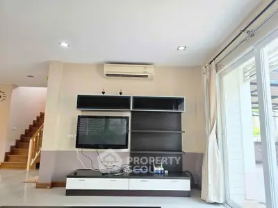Modern living room with sleek TV unit and large windows for natural light.