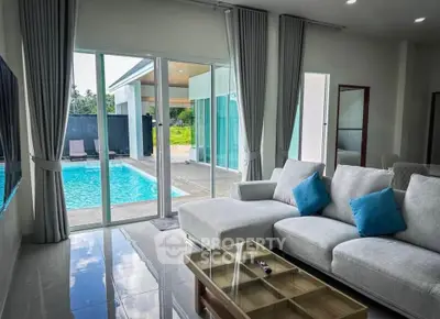 Luxurious living room with pool view, modern sofa, and glass doors opening to a private pool area.