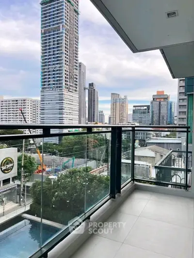Modern balcony with glass railing offering stunning cityscape views in a high-rise building.