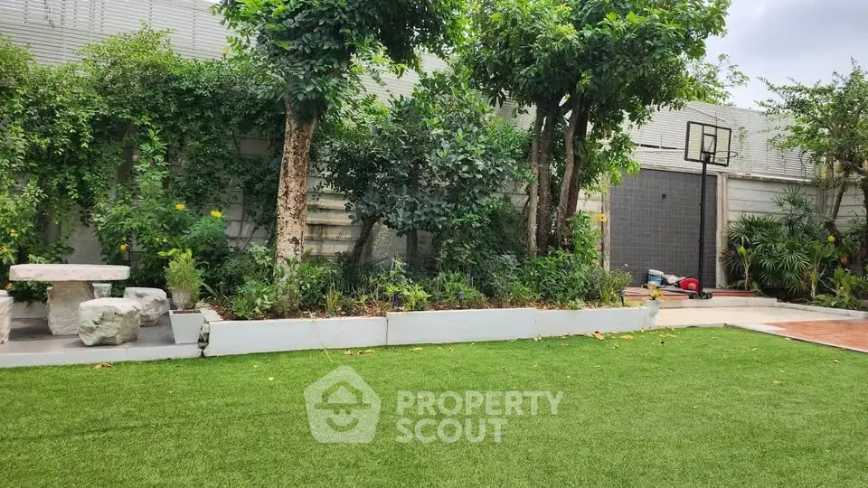 Spacious backyard with lush greenery and basketball hoop, perfect for outdoor activities.