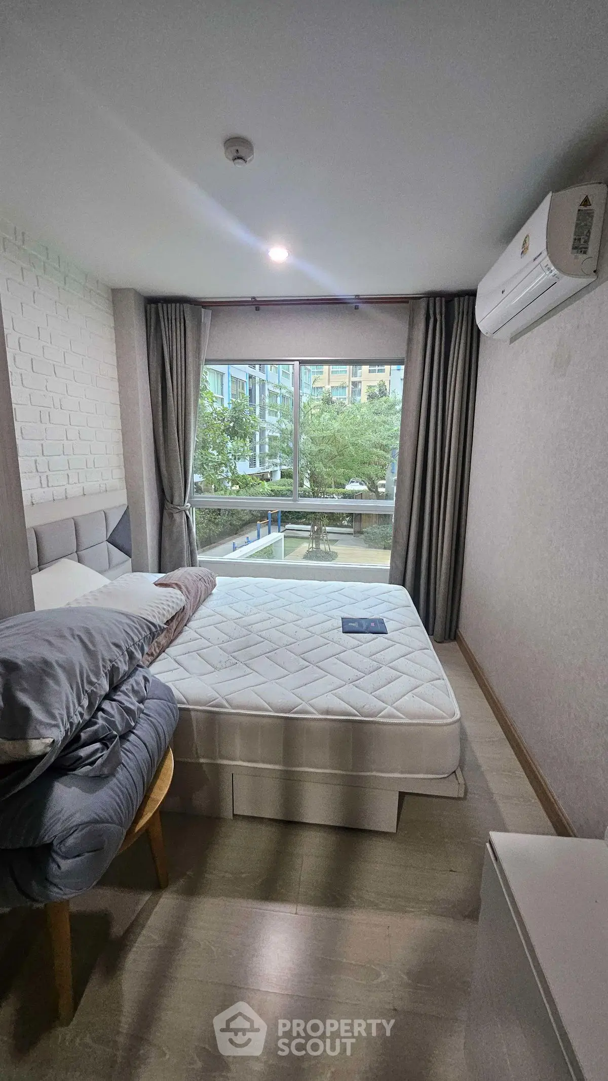 Cozy bedroom with large window and air conditioning in modern apartment.